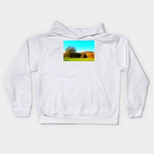 Beautiful scenery with green meadow, sprawling tree and mountains covered by autumn colored forests Kids Hoodie